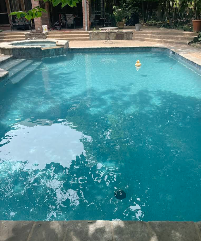 A sparkling blue pool surrounded by stone coping.