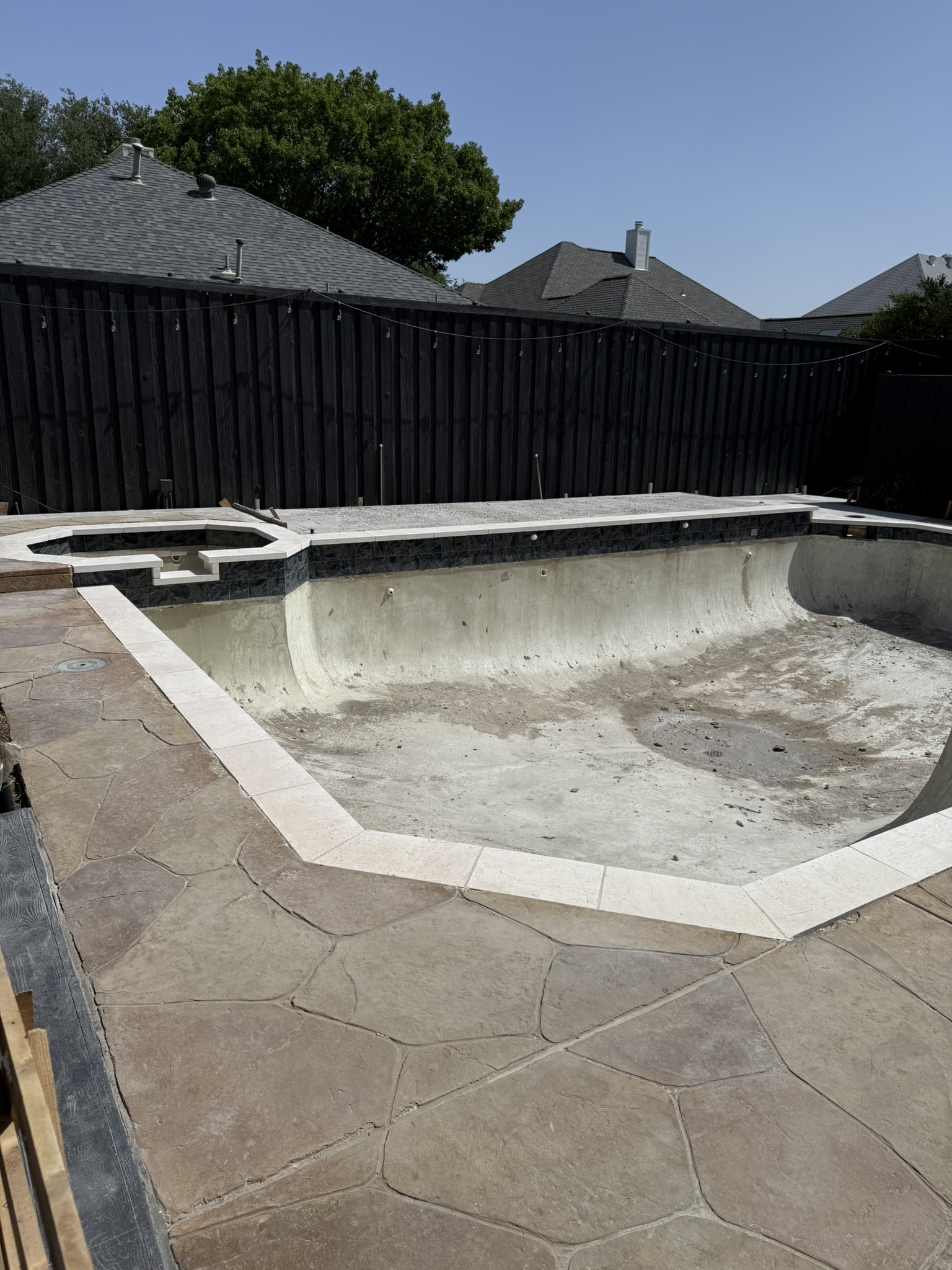 Empty swimming pool under renovation, featuring cracked concrete and unfinished decking.