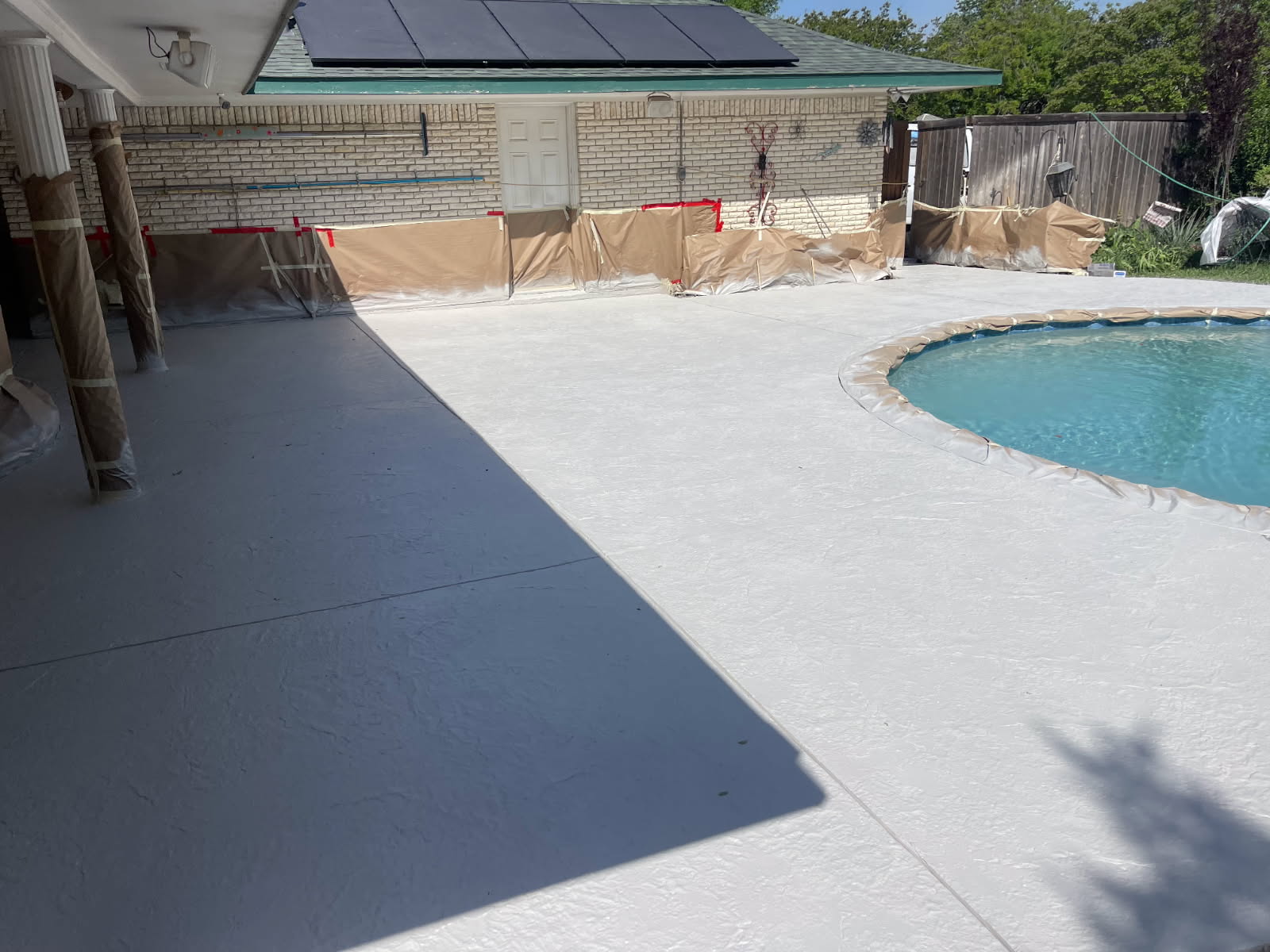 Recently resurfaced pool deck with a clear view of the swimming pool, featuring a protective edge around the pool and a well-maintained outdoor area.
